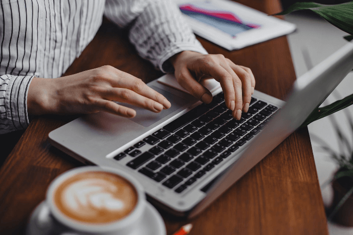 Autónomo gestionando su negocio online con ordenador portátil y café Autónomo gestionando su negocio online con ordenador portátil y café