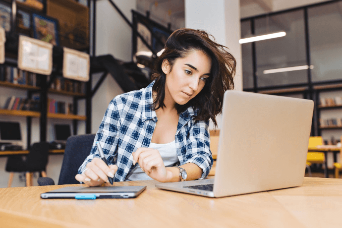 Autónoma gestionando su negocio online desde ordenador portátil en oficina Autónoma gestionando su negocio online desde ordenador portátil en oficina