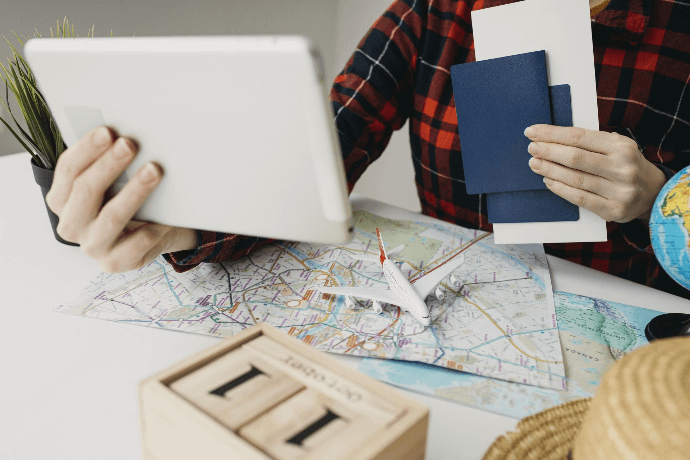 Persona con tablet, mapa y pasaportes planificando un viaje Persona con tablet, mapa y pasaportes planificando un viaje