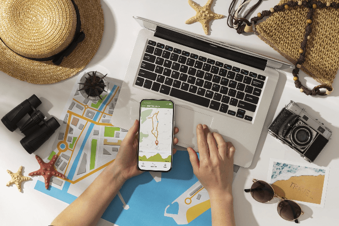 Mano señalando un globo terráqueo con pasaporte y cámara para planificación de viaje Organización de vacaciones con mapa en smartphone y portátil