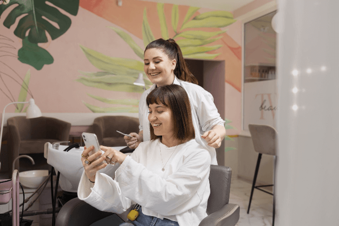 Estilista y cliente disfrutando de sesión de peluquería en salón moderno Estilista y cliente disfrutando de sesión de peluquería en salón moderno