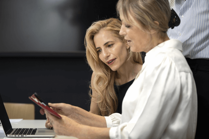 Consultora de belleza revisando reservas en línea con cliente en salón Consultora de belleza revisando reservas en línea con cliente en salón