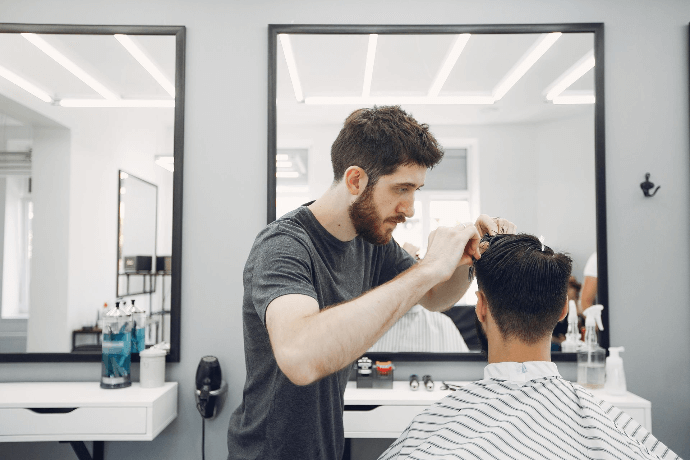 Estilista cortando el cabello a cliente en peluquería moderna Estilista cortando el cabello a cliente en peluquería moderna
