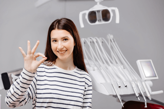 Paciente satisfecha mostrando señal de OK en clínica dental Paciente satisfecha mostrando señal de OK en clínica dental