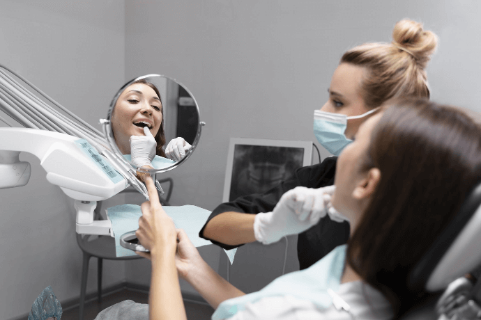 Paciente mirando su sonrisa en el espejo después de tratamiento dental Paciente mirando su sonrisa en el espejo después de tratamiento dental