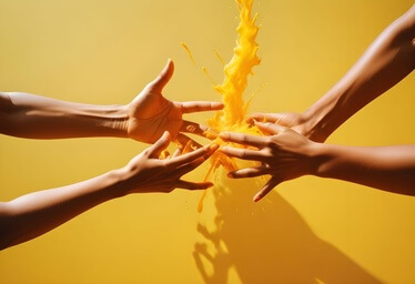 Manos interactuando con salpicadura de líquido naranja en fondo amarillo Manos interactuando con salpicadura de líquido naranja en fondo amarillo