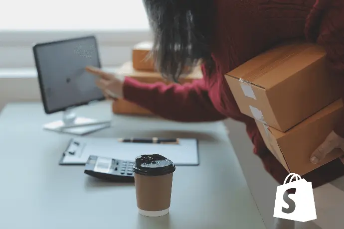 Persona gestionando paquetes frente a ordenador, migración de tienda a Shopify Persona gestionando paquetes frente a ordenador, migración de tienda a Shopify